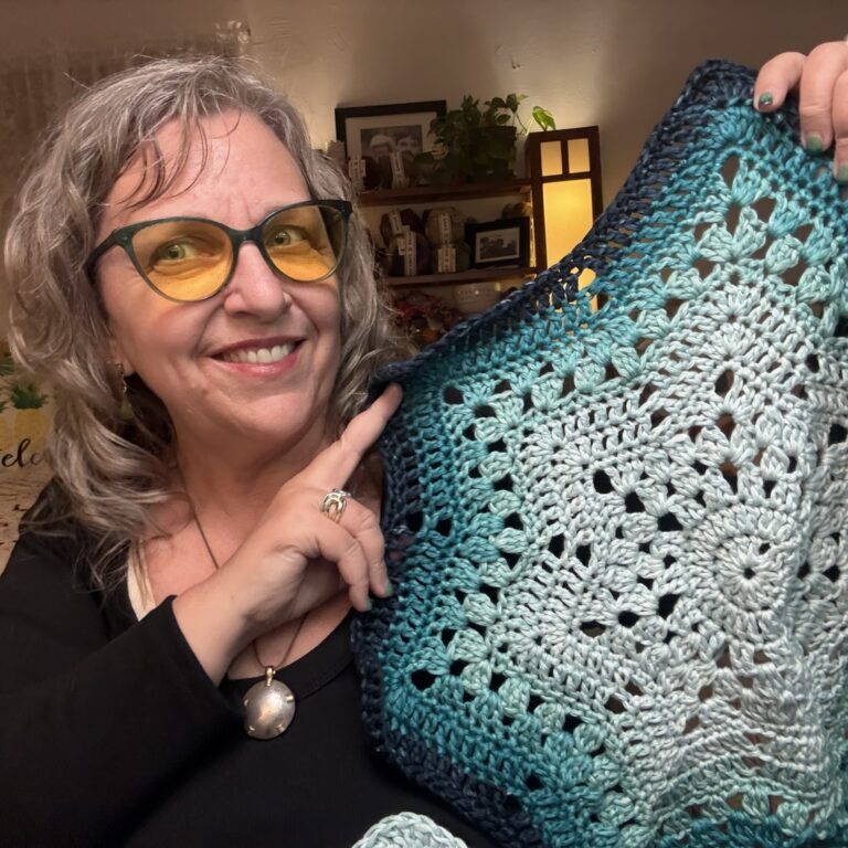 Beth McKee Elliott aka Betty McKnit holding up crochet project in progress.